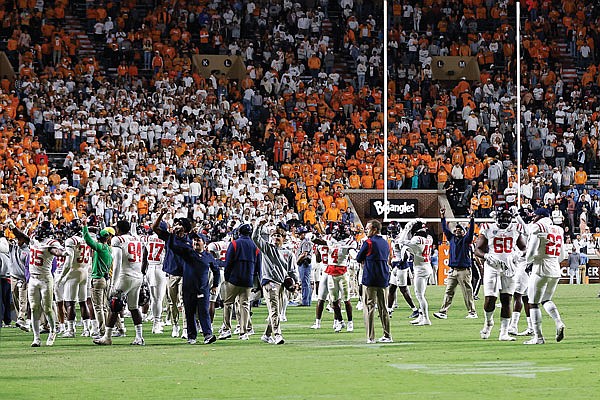 Mississippi players stand on the field after Saturday night's game against Tennessee was delayed because of fans throwing items onto the field late in the second half in Knoxville, Tenn.
