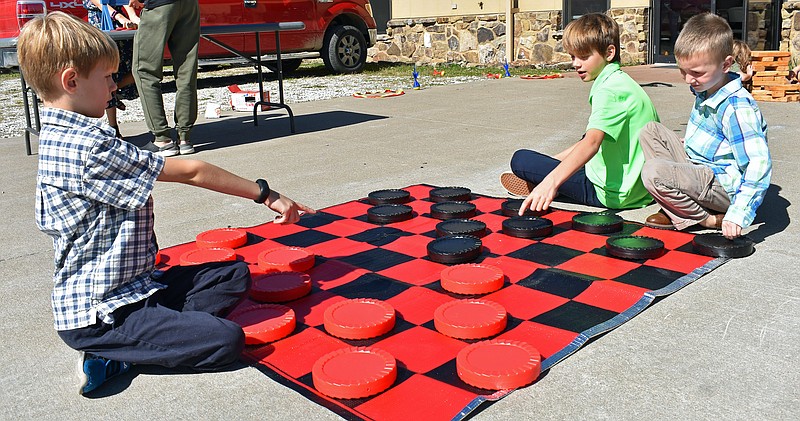 Gerry Tritz/News Tribune
From left, Landon Diener, 6, Matthew Garoutte, 10, and Caleb Garoutte, 7, play an oversized game of checkers at Grace Lutheran Church's first GraceFest, a celebration of the church's faith and German Heritage.
