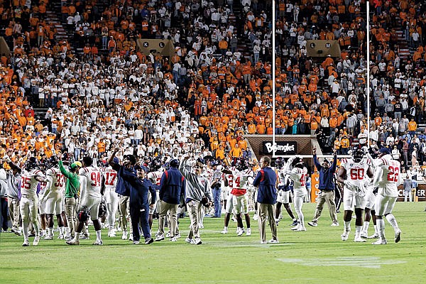 Mississippi players stand on the field Saturday night after the game against Tennessee was delayed because of fans throwing bottles onto the field late in the second half in Knoxville, Tenn.