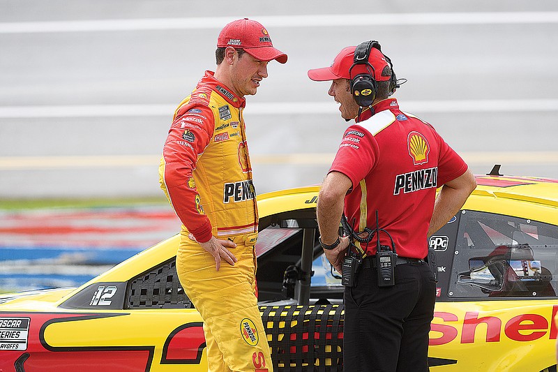 Joey Logano talks with a crew member as his car sits parked on pit row during a rain delay in a NASCAR Cup Series race earlier this month in Talladega, Ala.