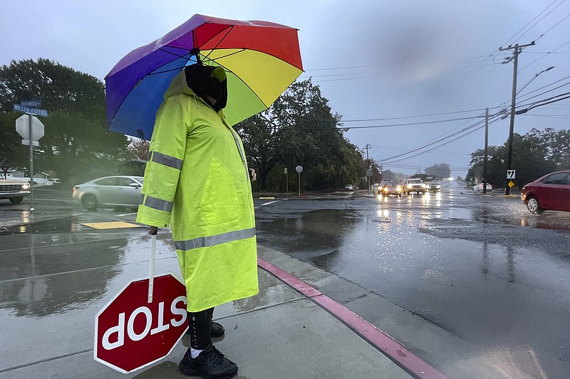 Crossing guard Katy Bredahl is pelted with rain while keeping an eye out for children on Marinwood Avenue in San Rafael, Calif., on Thursday, Oct. 21, 2021. Northern California residents delighted by this week's rain were cleaning up Friday and preparing for a massive storm this weekend, happy the precipitation has helped contain stubborn wildfires but fearful of flash flooding in vast areas already scorched by fire. (Sherry LaVars/Marin Independent Journal via AP)