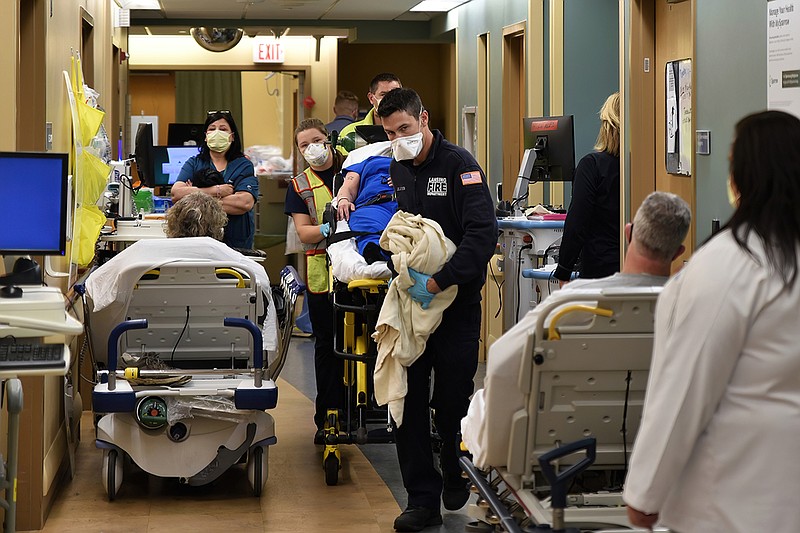 An ambulance crew weaves a gurney through the halls of the emergency department at Sparrow Hospital in Lansing, Michigan. Overcrowding has forced staff members to triage patients, putting some in the waiting rooms, and treating others on stretchers and chairs in the halls. (Lester Graham/Kaiser Health News/TNS)