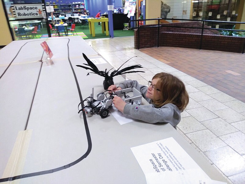 (Submitted by LabSpace Robotics) A participant in a previous robot race holds her robot at LabSpace Robotics' main location in Capital Mall.