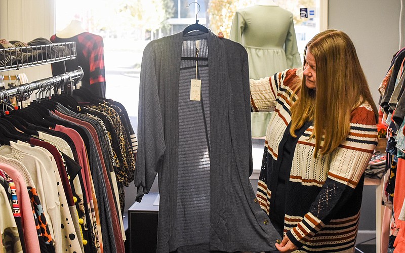 (India Garrish/News Tribune) Mattie Grace Boutique Owner Sheila Berhorst shows a cardigan Nov. 10 with button accents. Clothing items like cardigans can be a great transitional piece into the winter months.