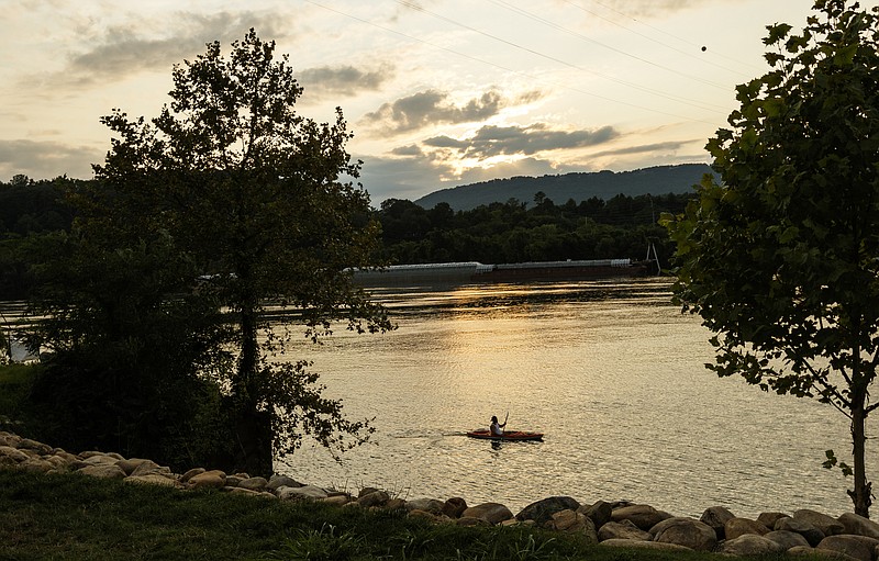 A kayaker launched from the Tennessee Riverpark paddles on the Tennessee River on Tuesday, Aug. 8, 2017, in Chattanooga, Tenn. Chattanooga is joining other towns along the Tennessee River in a partnership to promote paddling and other recreational activities. (Doug Strickland/Chattanooga Times Free Press via AP)