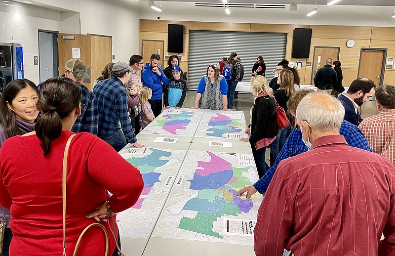 <p>Community members gather around the tables with maps of different boundary line scenarios Monday at Capital City High School as JC Schools Chief of Operations Dawn Berhorst answers questions.</p>