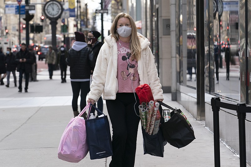 FILE - In this Dec. 10, 2020 file photo, a woman carries shopping bags in New York. The National Retail Federation expects that holiday sales gain could shatter last year’s record-breaking season even as a snarled global supply chain slows the flow of goods and results in higher prices for broad range of items. The nation's largest retail trade group said Wednesday, Oct. 27, 2021 it predicts that sales for the November and December period will grow between 8.5% and 10.5% to $843.4 billion and $859 billion. (AP Photo/Mark Lennihan, File)