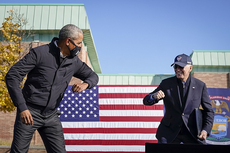 Former U.S. President Barack Obama and Democratic presidential nominee Joe Biden greet each other with a socially distant "air" elbow bump at the end of a drive-in campaign rally at Northwestern High School on Oct. 31, 2020 in Flint, Michigan. (Drew Angerer/Getty Images/TNS)