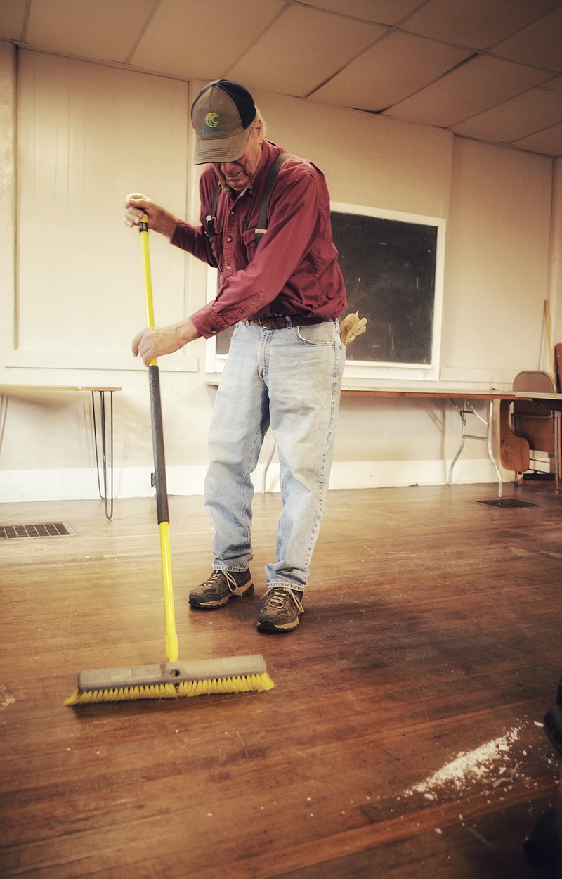 Palmer Ott sweeps up broken glass from fluorescent light bulbs in the Lohman Community Center Saturday. Ott and others town members gathered to clean up after vandals struck the center.