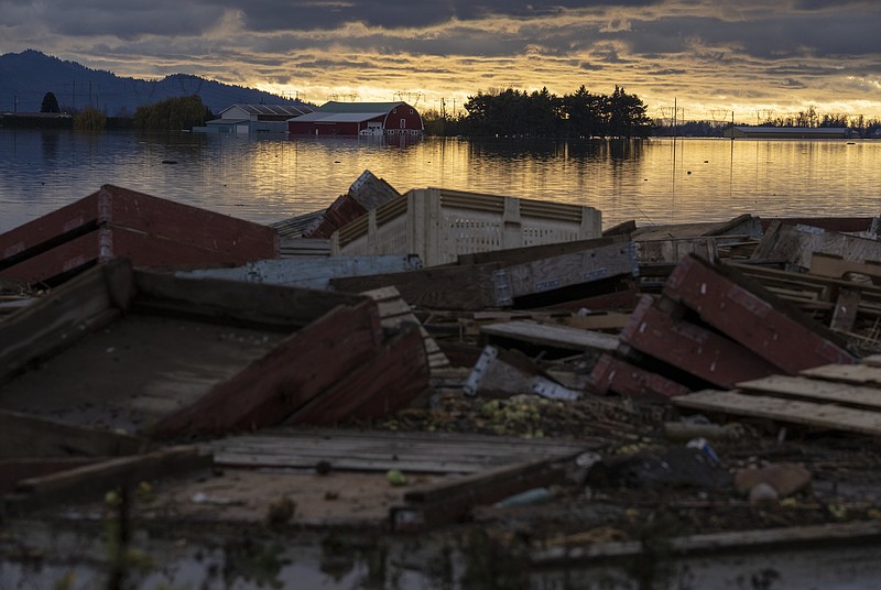 Debris is piled up as farms are surrounded by floodwaters caused by heavy rains and mudslides in Abbotsford, British Columbia, Friday, Nov. 19, 2021. (Jonathan Hayward/The Canadian Press via AP)
