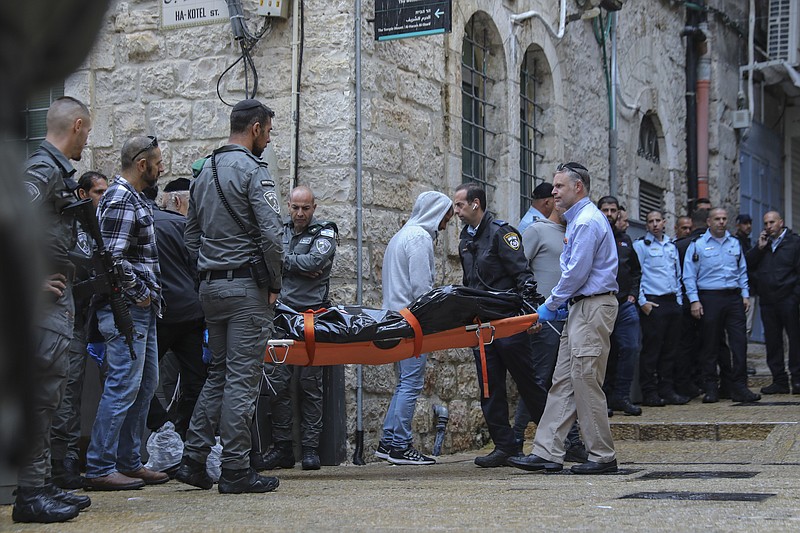 Israeli security personnel and members of Zaka Rescue and Recovery team carry the body of a Palestinian man who was fatally shot by Israeli police after he killed one Israeli and wounded four others in a shooting attack in Jerusalem's Old City, Sunday, Nov. 21, 2021. (AP Photo/Mahmoud Illean)