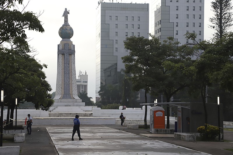 FILE - A police officer from the mayor's office patrols near the Chivo digital wallet machine, which will exchange cash for Bitcoin cryptocurrency, right, in Las Americas Square in San Salvador, El Salvador, Sept. 7, 2021, the day when all businesses must start accepting payments in Bitcoin, except those lacking the technology to do so. (AP Photo/Salvador Melendez, File)