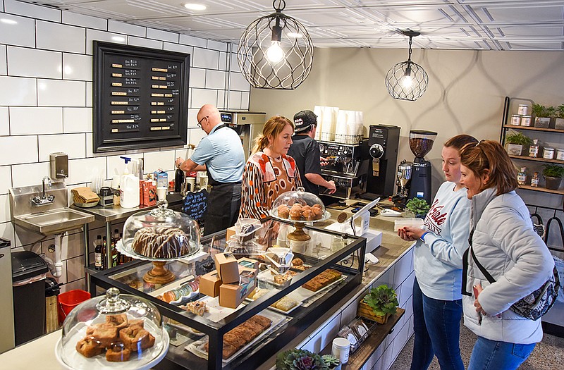 Melanie Stockman, right, and her daughter, Sophia, look over pastry options on the counter at Plate & Pour, a new coffee and pastry shop located in the bottom floor of the Missouri Baptist Building on East High Street. Behind the counter are, from left, Roger Whitmore, Laura Whitmore and their son, Tanner. The Whitmores are the owners of Plate & Pour.