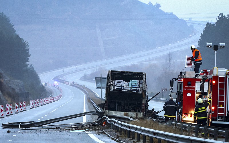 Firefighters and forensic workers inspect the scene of a bus crash which, according to authorities, killed at least 45 people on a highway near the village of Bosnek, western Bulgaria, Tuesday, Nov. 23, 2021. The bus, registered in Northern Macedonia, crashed around 2 a.m. and there were children among the victims, authorities said. (Minko Chernev/BTA Agency Bulgaria via AP)