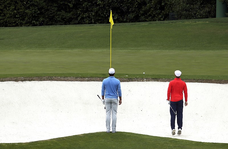 In this April 10, 2016, file photo, Brooks Koepka (left) watches as Bryson DeChambeau jumps up in a bunker to see his ball on the fourth green during the final round of the Masters in Augusta, Ga.