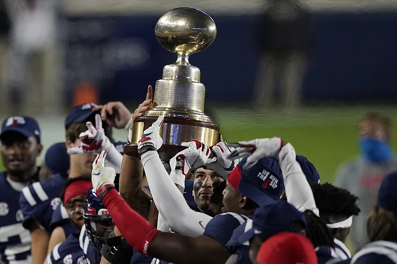 In this Nov. 28, 2020, file photo, Mississippi quarterback Matt Corral looks up at the Egg Bowl trophy beating in state rival Mississippi State 31-24 in Oxford, Miss.