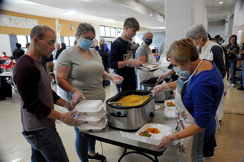 Volunteers prepare Thanksgiving meals to go at the Immaculate Conception Church. On left is Matt Hayes, in the gray-colored shirt is Molly Hutson, and on right is Janie Frank.