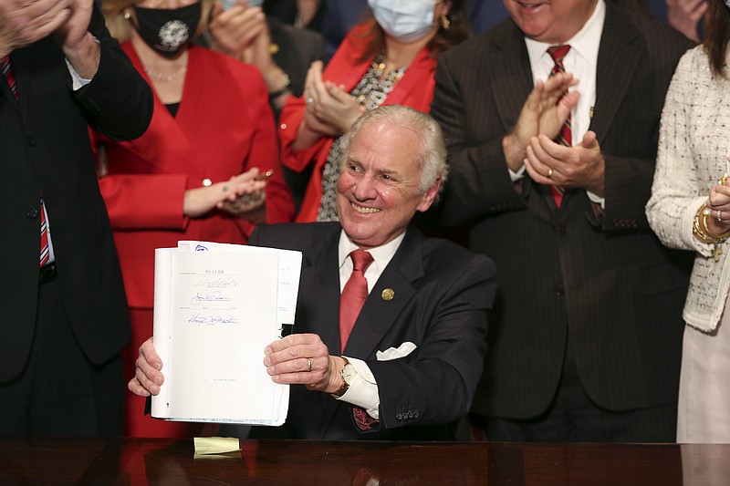 FILE - South Carolina Gov. Henry McMaster holds up a bill banning almost all abortions in the state after he signed it into law on Thursday, Feb. 18, 2021, in Columbia, S.C.  Appellate arguments over a lawsuit challenging South Carolina’s abortion law have been pushed into the new year. Oral arguments in the case had originally been planned for next month, but the 4th U.S. Circuit Court of Appeals has rescheduled them for the last week in January 2022, according to an order from the court. (AP Photo/Jeffrey Collins, File)