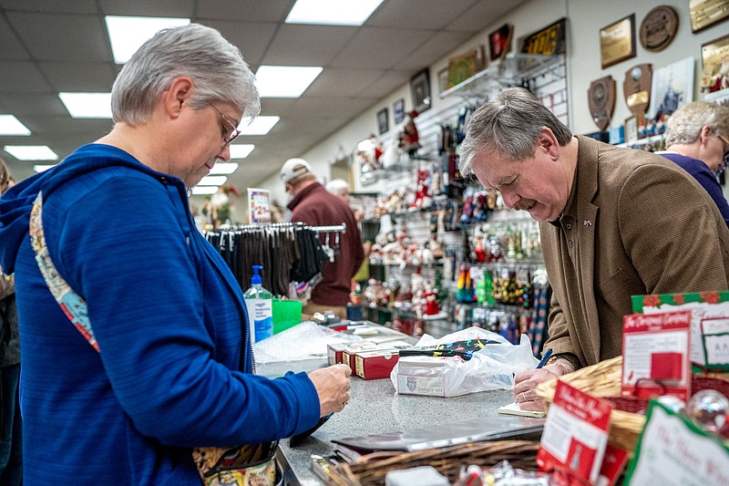 Ethan Weston/News Tribune Sam Bushman writes a receipt for Leesa Love on Saturday at Samuel’s Tuxedos and Gifts in Jefferson City. Love buys “retro” toys for her husband from Samuel’s every year.