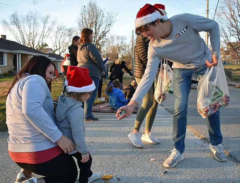 Gerry Tritz/News Tribune
At right, Evan Kliethermes hands candy to Ivy Plassmeyer as mother Danielle Plassmeyer looks on during Sunday's Christmas parade in Westphalia.