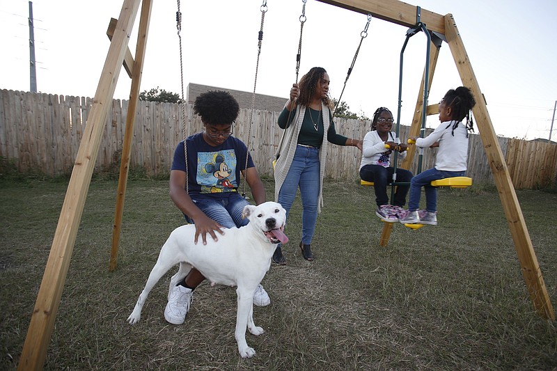 Rosalia Tejeda, second from left, plays with her children, from left, son Juscianni Blackeller, 13; Adaliana Gray, 5, and Audrey Gray, 2, in their backyard in Arlington, Texas, Monday, Oct. 25, 2021. As Tejeda, 38, has learned more about health risks posed by fracking for natural gas, she has become a vocal opponent of a plan to add more natural gas wells at a site near her home. (AP Photo/Martha Irvine)