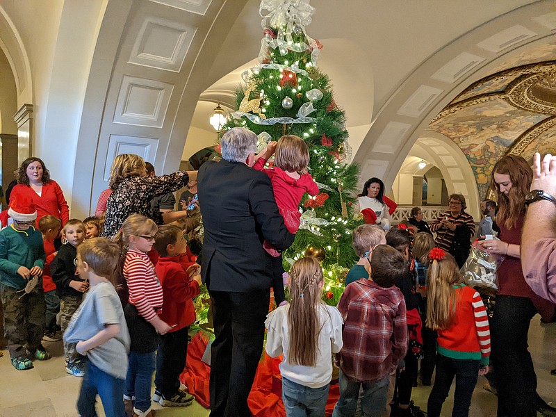 Gov. Mike Parson admires the Capitol Christmas tree with a kindergarten class from Eugene Elementary School. The tree is a 10-foot Loblolly Pitch supplied by Steve and Teresa Meier of Meier Horseshoe Pines in Jackson, Missouri. Photo by Ryan Pivoney
