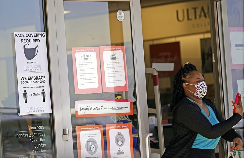 A customer exits a store with a mask required sign displayed, Tuesday, March 2, 2021, in Dallas. (AP Photo/LM Otero)