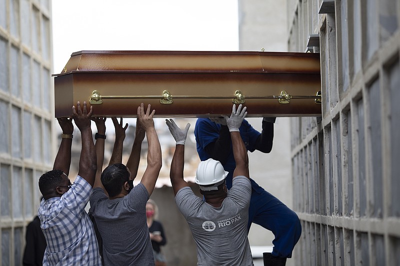 FILE - In this April 13, 2021, file photo, the remains of a woman who died from complications related to COVID-19 are placed into a niche by cemetery workers and relatives at the Inahuma cemetery in Rio de Janeiro, Brazil. The global death toll from the coronavirus topped a staggering 3 million people Saturday, April 17, 2021, amid repeated setbacks in the worldwide vaccination campaign and a deepening crisis in places such as Brazil, India and France. (AP Photo/Silvia Izquierdo, File)