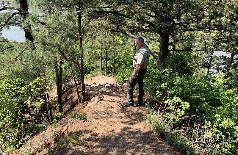 Park Ranger Ian Hope looks off the side of a dirt path in Emerald Park that crosses over the cliffs around Big Rock Quarry. Officials say the path, which is not part of the park trail, is dangerous and visitors need to stay away from it.