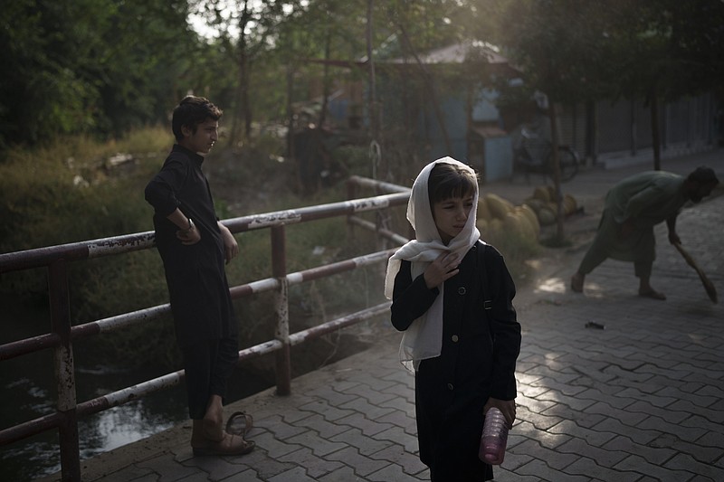 A girl waits for her friends as they walk to school in Kabul, Afghanistan, Sunday, Sept. 12, 2021. (AP Photo/Felipe Dana)