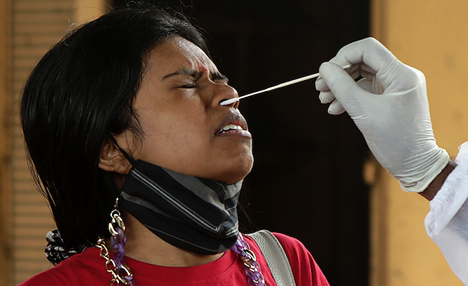 A health worker collects a swab sample from traveler at a railway station to test for the coronavirus before allowing her to enter the city, in Mumbai, India, Tuesday, Dec. 7, 2021. (AP Photo/Rajanish Kakade)