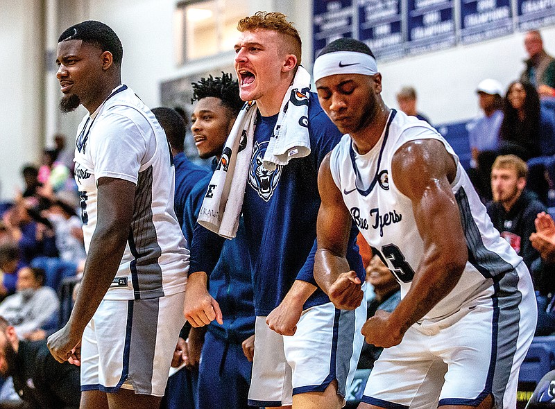 (From left) Derrick Woods, Mark Boland and Josh Wallace celebrate after a teammate made a basket during last week’s game against Central Christian College of the Bible at Jason Gym.