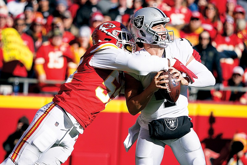 Raiders quarterback Derek Carr is sacked by Chiefs defensive end Frank Clark during Sunday afternoon’s game at Arrowhead Stadium. (Associated Press)