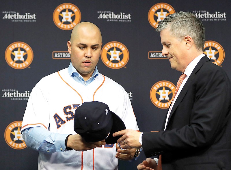 In this Dec. 5, 2016, file photo, Astros general manager Jeff Luhnow (right) hands outfielder Carlos Beltran a cap during a news conference to announce Beltran’s signing a one-year contract with the team in Houston. (Associated Press)