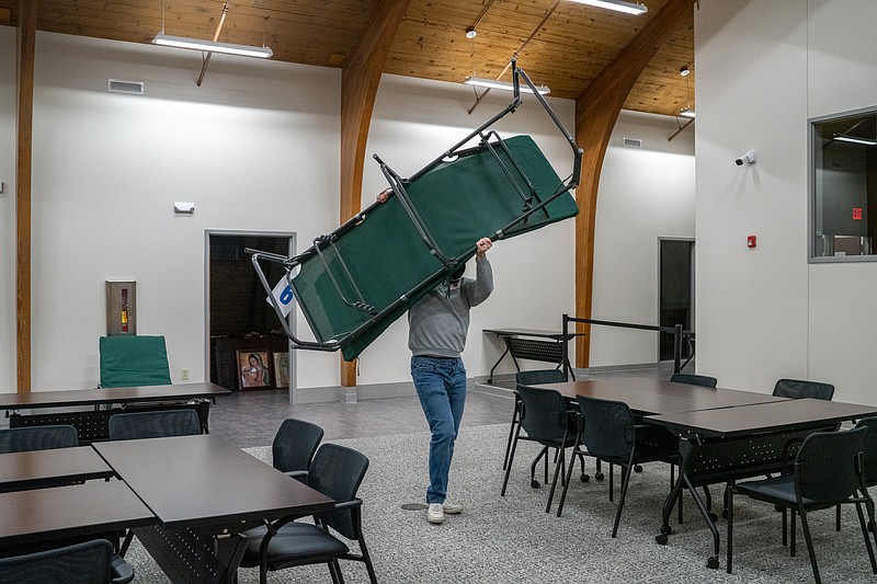 Aaron Washburn carries a cot across the room Feb. 4 at the Jefferson City Room at the Inn warming center inside Catholic Charities. (Ethan Weston/News Tribune)