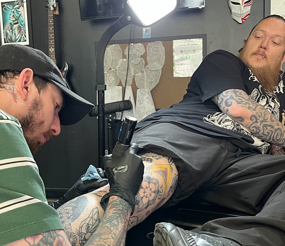 Quest May, left, son of Body of Art owner Kara May, tattoos Josh Hildebrandt on Tuesday in Texarkana, Texas. Body of Art, like other tattoo shops in the Texarkana area, was able to open up and continue tattooing following a two month shut down in the spring of 2020. (Staff photo by James Bright)