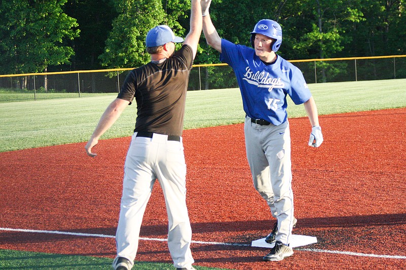 South Callaway sophomore Owen Rees celebrates with head coach Heath Lepper after sliding into third base with a game-tying triple against Montgomery County in Monday’s Class 3 District 7 semifinal game in Mokane. Senior Jacob Lallier hit a double afterward to give the Bulldogs a 6-5 lead. (Jeremy Jacob/FULTON SUN)