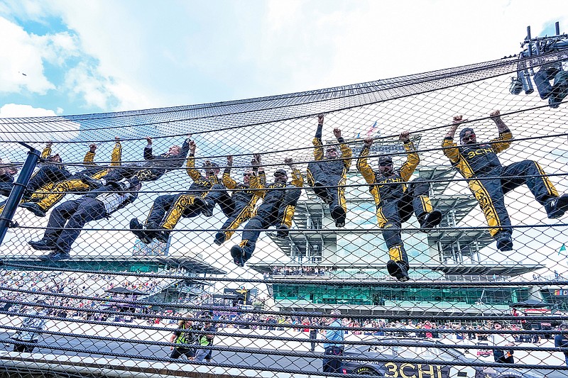 Tyler Reddick (in fire suit with black arms) climbs the fence with his crew after winning Sunday’s NASCAR Cup Series race at Indianapolis Motor Speedway in Indianapolis. (Associated Press)