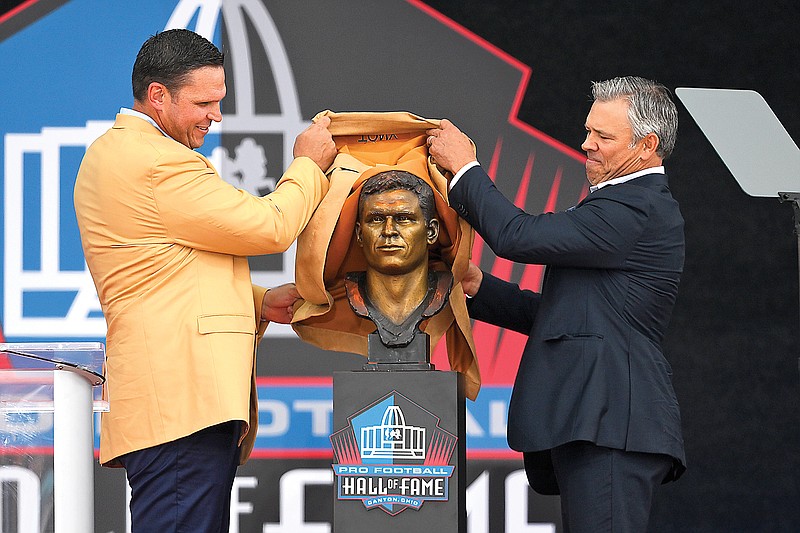 Former NFL player Tony Boselli (left) and his presenter Mark Brunell unveil Boselli’s bust before speaking Saturday during his induction into the Pro Football Hall of Fame in Canton, Ohio. (Associated Press)