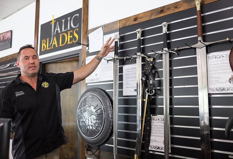 Staff photo by Olivia Ross / Chris Beasley, owner of Jalic Blades, discusses different items on the walls on August 23, 2022. Jalic Blades has world-exclusive rights to manufacture replica weapons from George R.R. Martin's 'A Song of Ice and Fire' and 'Game of Thrones.'