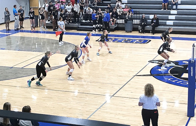 Capital City volleyball players wait to receive the ball on a serve from Warrensburg during Thursday night's match at Capital City High School. (Greg Jackson/News Tribune)