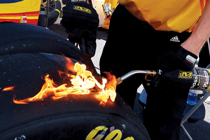 A pit crew member for Michael McDowell cleans debris from a tire during last Sunday afternoon's NASCAR Cup Series race in Talladega, Ala. (Associated Press)