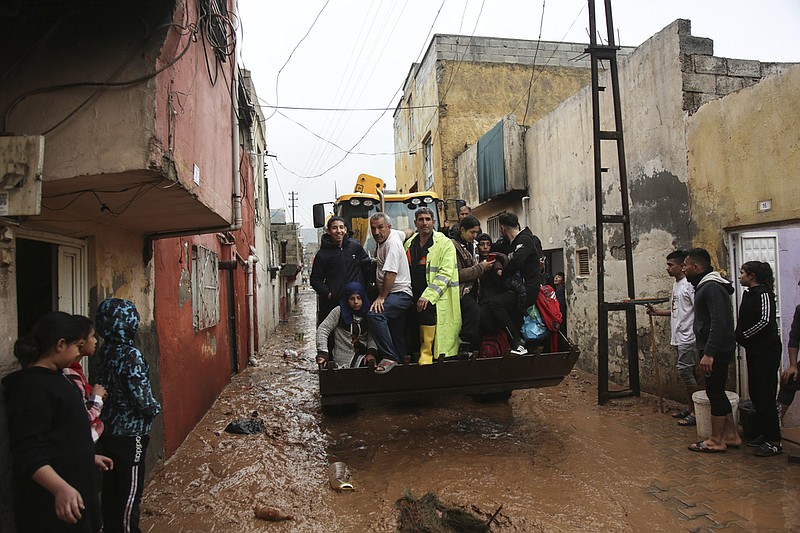 People are rescued during floods after heavy rains in Sanliurfa, Turkey, Wednesday, March 15, 2023. Floods caused by torrential rains hit two provinces that were devastated by last month's earthquake, killing at least 10 people and increasing the misery for thousands who were left homeless, officials and media reports said Wednesday. At least five other people were reported missing. (Hakan Akgun/DIA via AP)