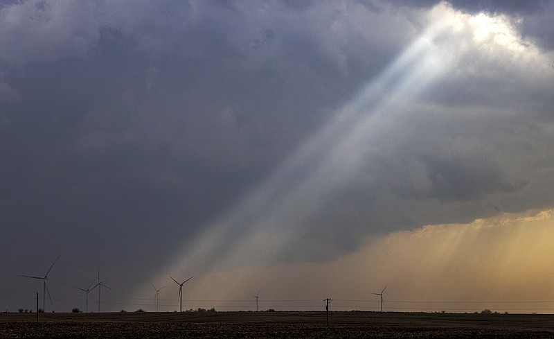Sunlight filters through storm clouds onto a wind turbine as severe weather rolls through the midwest on Tuesday, April 4, 2023, south of Stuart, Iowa. Strong storms, likely including tornadoes, are expected to hit parts of the Midwest and South beginning Tuesday evening. (Chris Machian/Omaha World-Herald via AP)