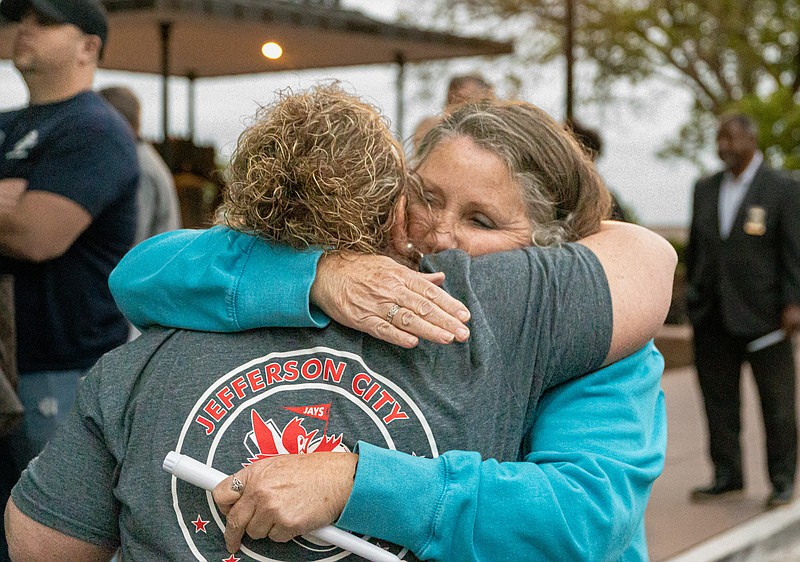 Laura Ruediger hugs Judy Tinnin while handing out electronic candles during the Law Enforcement Candlelight Vigil at the Capitol on Friday night. Electronic candles were used this year instead of actual candles due to the wind.