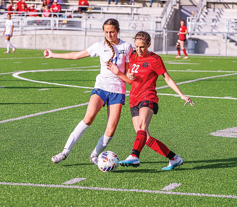 Capital City’s Kassi Loethen fights for control of the ball against Ozark’s Morgan Pickens during Friday night’s game at Capital City High School. (Ken Barnes/News Tribune)