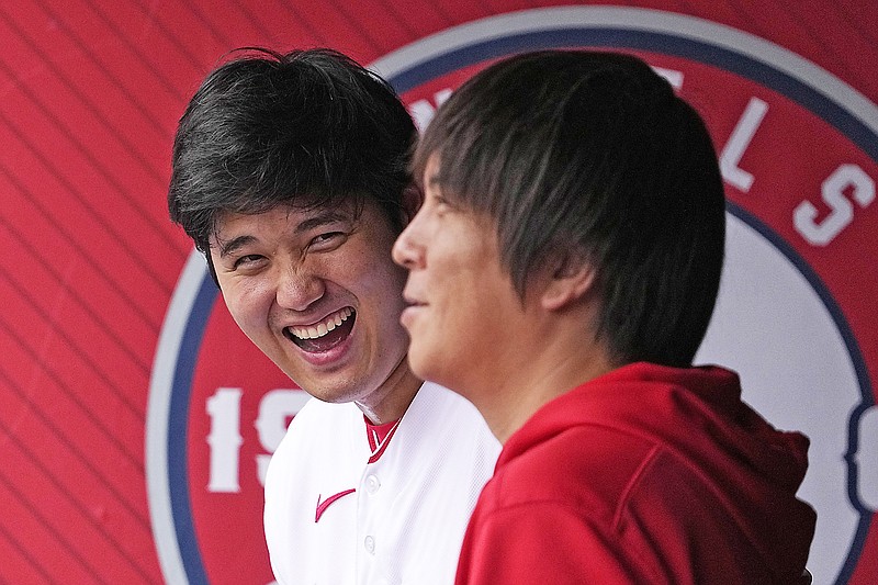Shohei Ohtani of the Angels (left) laughs as he talks to interpreter Ippei Mizuhara prior to Sunday's game against the Pirates in Anaheim, Calif. (Associated Press)