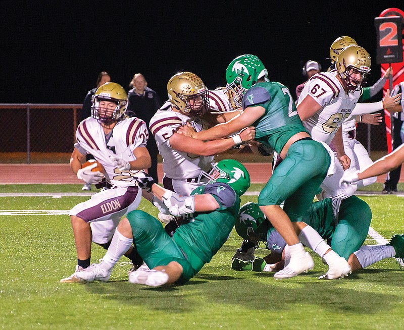Blair Oaks defensive lineman Jaxon Marshall (center) attempts to tackle Eldon running back Braden Wrye (left) during Friday night’s game at the Falcon Athletic Complex in Wardsville. (Ken Barnes/News Tribune)