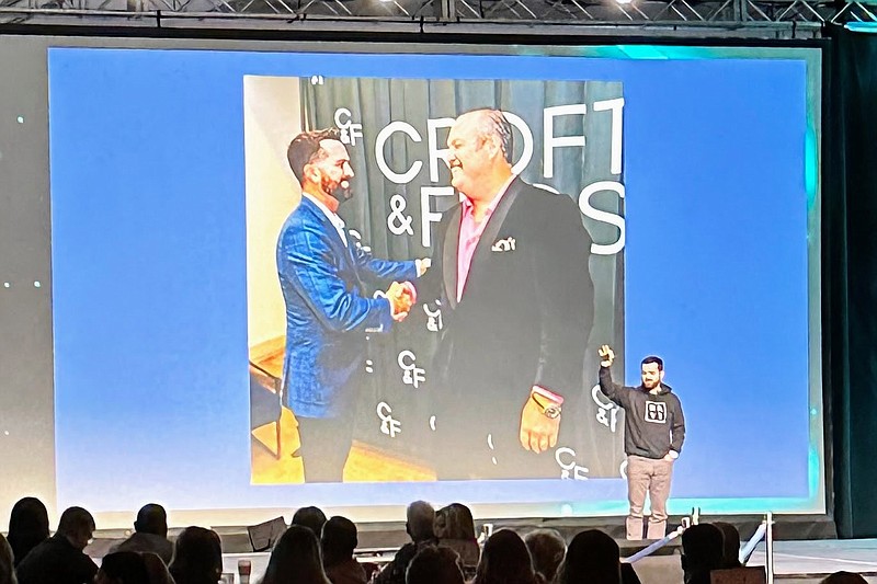 Contributed photo / Jonathan Frost is seen onstage at a business event, in front of a projected image celebrating his accounting and investing partnership with Paul Croft.