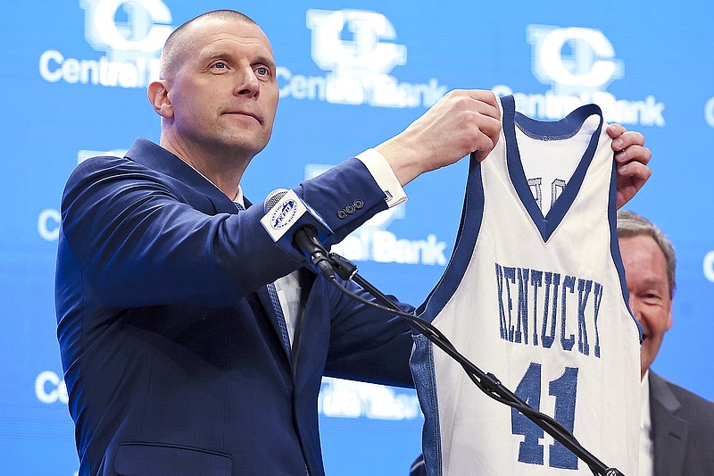 Mark Pope holds up his old playing jersey to fans and media after being named Kentucky men's NCAA college basketball head coach Sunday in Lexington, Ky. (Associated Press)